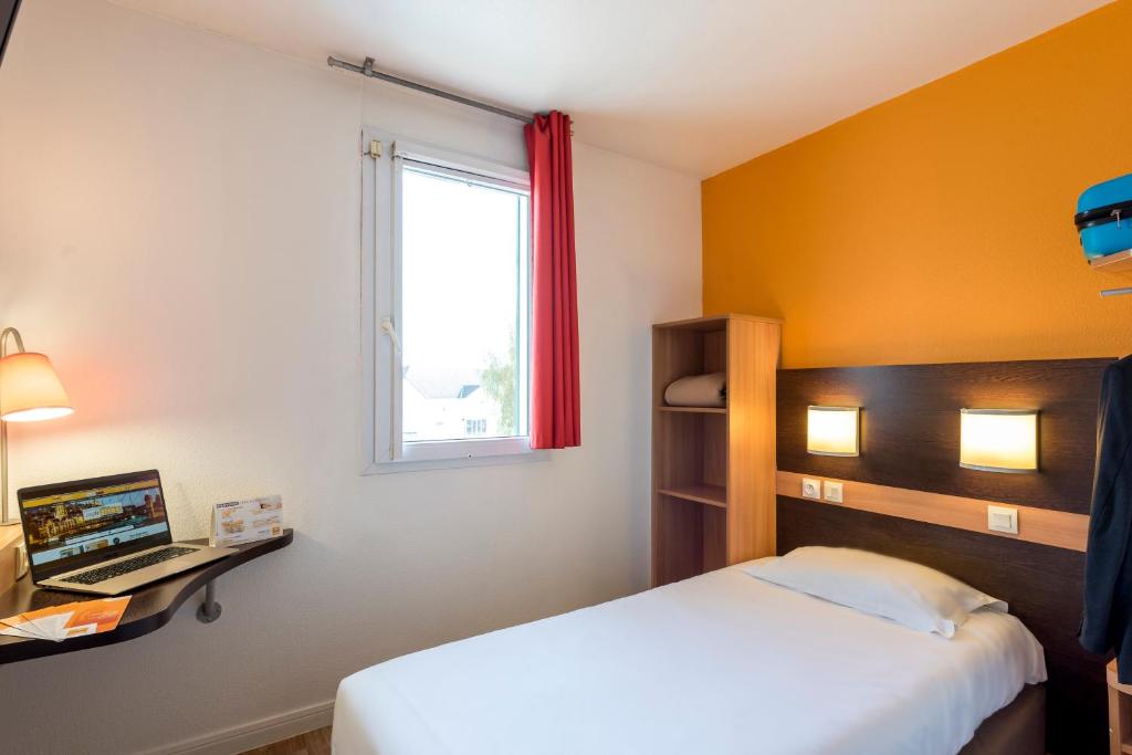 - une chambre avec un lit, une fenêtre et un ordinateur portable dans l'établissement Premiere Classe Annecy Nord - Epagny, à Épagny