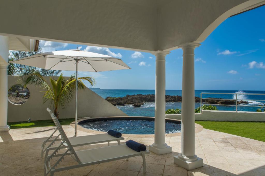 Trident Hotel في بورت أنطونيو: كرسي ومظله بجانب مسبح
