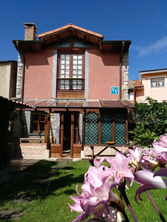 a pink house with a large window in the yard at Casa Rural El Ñeru in Llanes