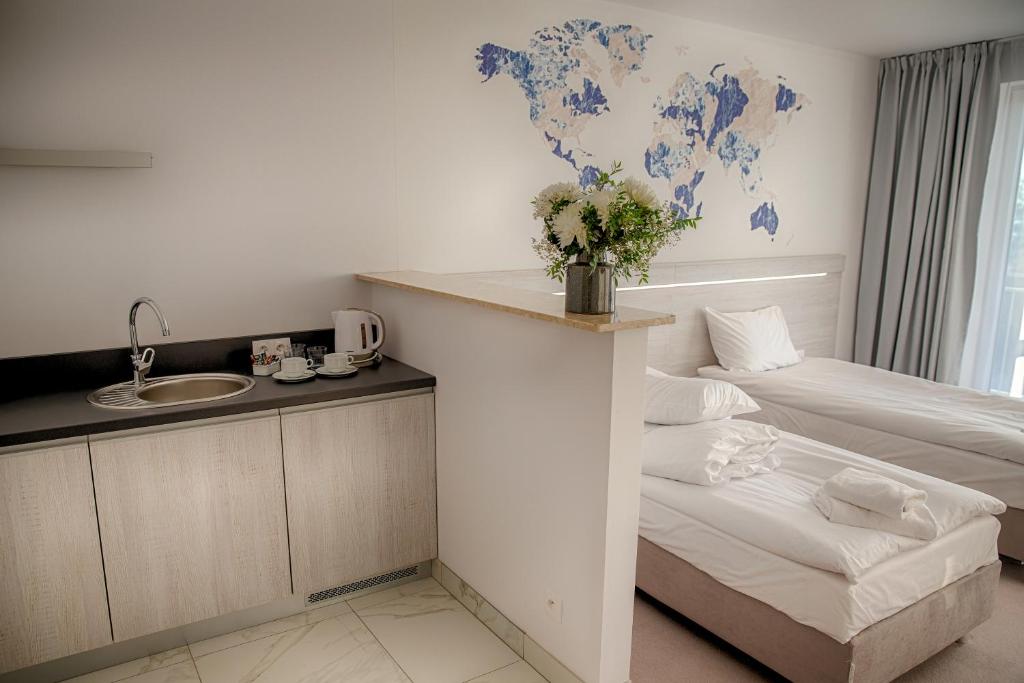 Small kitchenette beside two single beds, decorative world map, fresh flowers on divider.