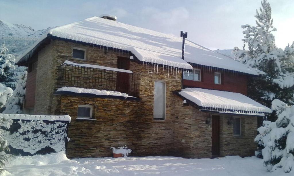 uma casa de tijolos com neve no telhado em Las Asturianas em San Carlos de Bariloche
