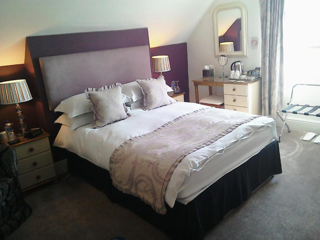 ein Schlafzimmer mit einem großen Bett mit weißer Bettwäsche und Kissen in der Unterkunft South Lodge Guest House in Bridlington