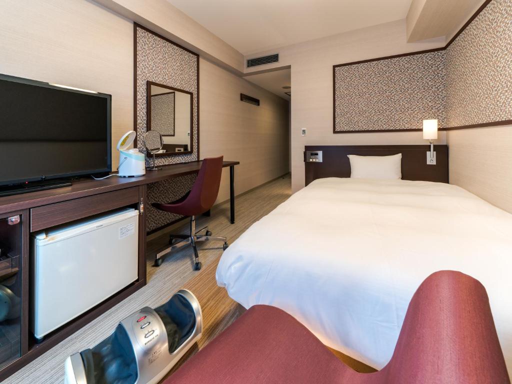 a hotel room with a bed and a flat screen tv at Daiwa Roynet Hotel Nagoya Eki Mae in Nagoya