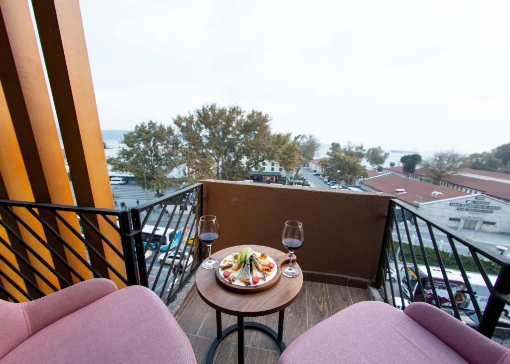 un balcone con tavolo e piatto di cibo e bicchieri da vino di Meydan Besiktas Hotel a Istanbul