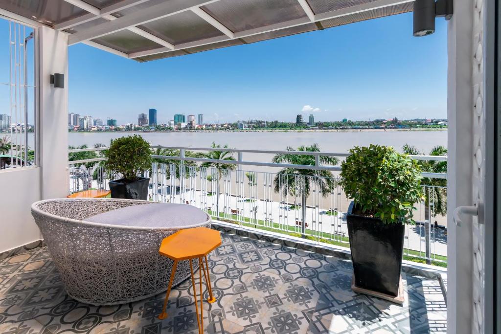 einen Balkon mit einem Tisch und Blick auf das Wasser in der Unterkunft TAO Riverside Residence in Phnom Penh