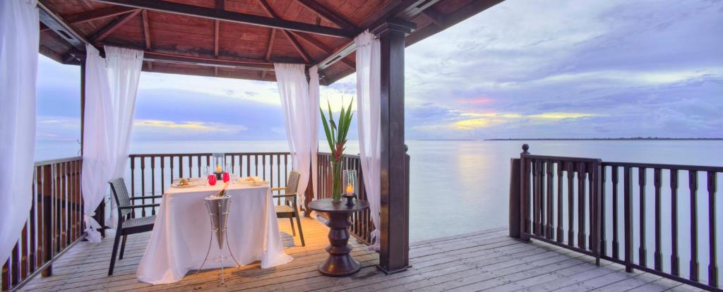 a table with a candle on a porch next to the water at The Residence Zanzibar in Kizimkazi