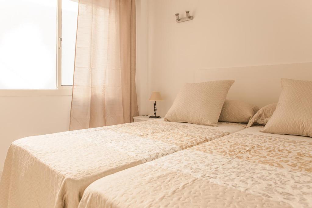フエンヒロラにあるAurinko 1 Tranquilo y Agradable Apartamento en Los Bolichesの白いベッドルーム(ベッド2台、窓付)