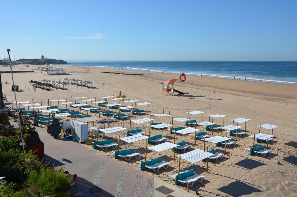 a beach with a bunch of chairs and the ocean at ABLA Guest House in Carcavelos