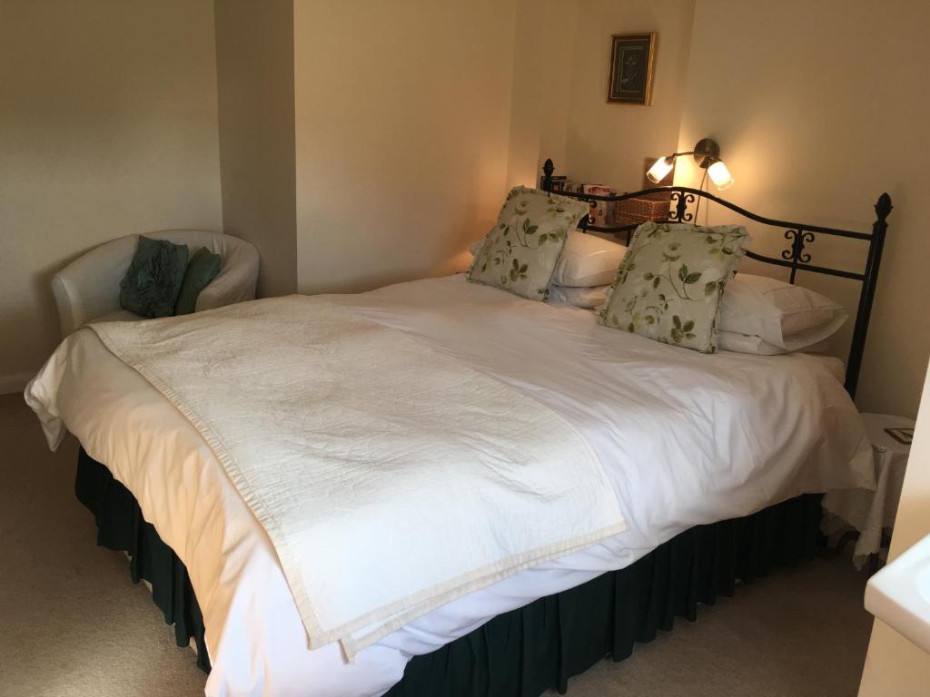 a bedroom with a bed with white sheets and pillows at The Poplars in Newbold on Stour