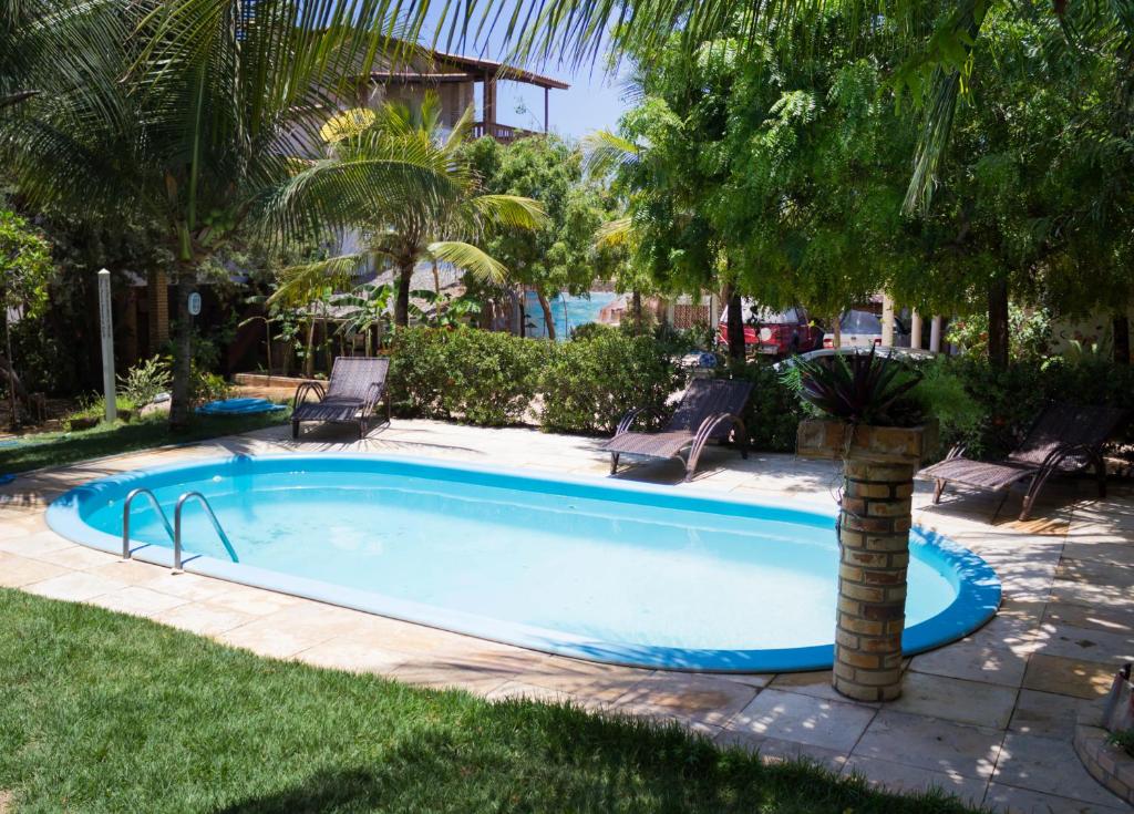 a swimming pool with a palm tree in a yard at Pousada Morada do Sol in Canoa Quebrada