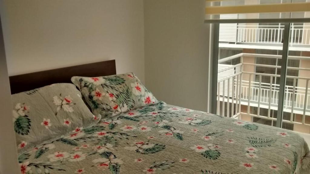 1 dormitorio con 1 cama con edredón de flores y ventana en Dpto La Serena, en La Serena