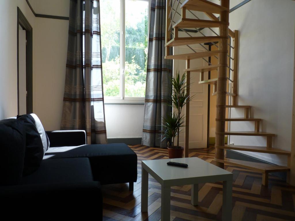 a living room with a staircase and a couch and a table at Pavillon Kalensa in Vals-les-Bains