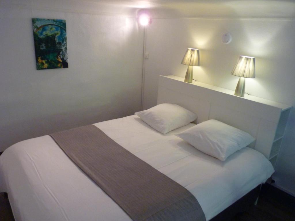 a bedroom with a white bed with two pillows at Pavillon Kalensa in Vals-les-Bains