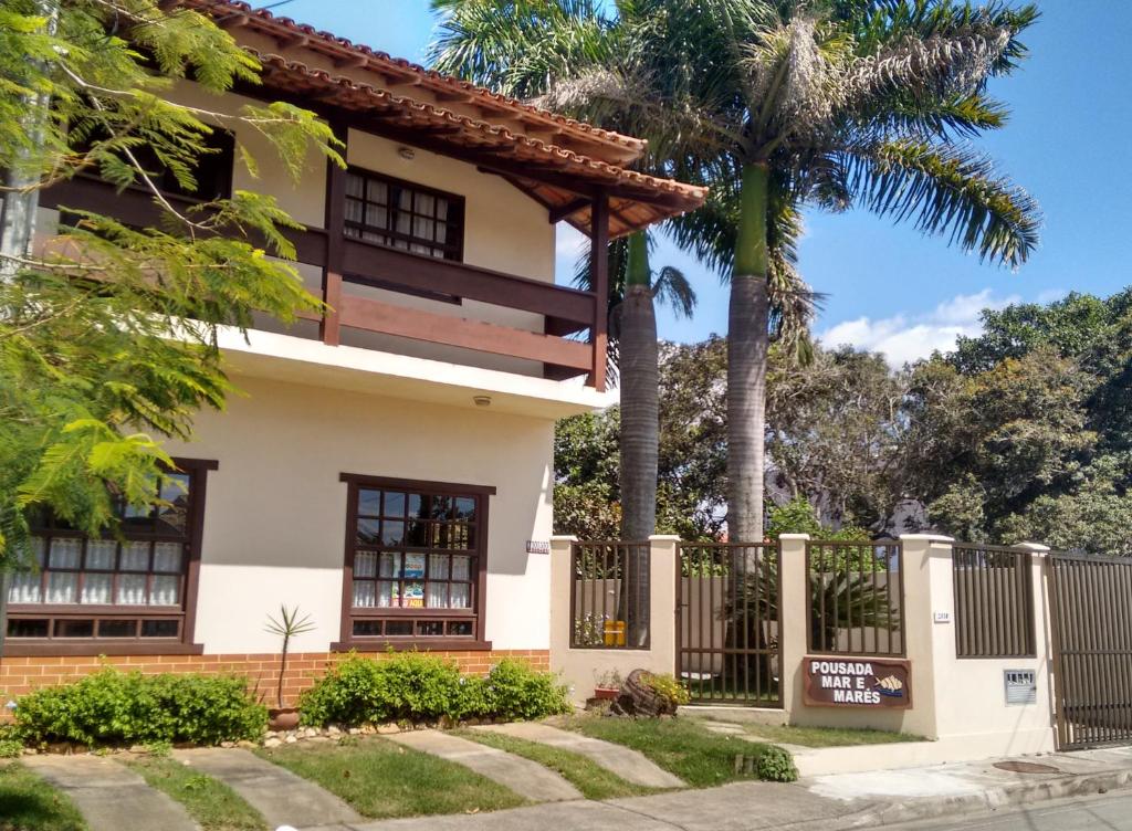 a house with a fence and a palm tree at Pousada Mar e Marés in Rio das Ostras