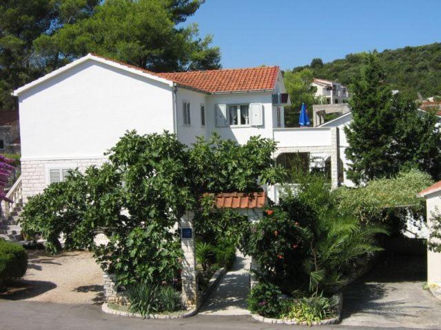 una casa blanca con árboles delante de ella en Apartments Sarah, en Korčula