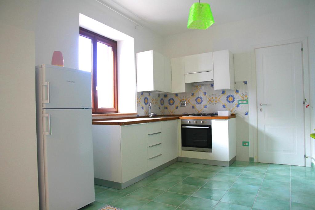 a kitchen with white cabinets and a refrigerator at Appartamento ALICANTE in Canneto