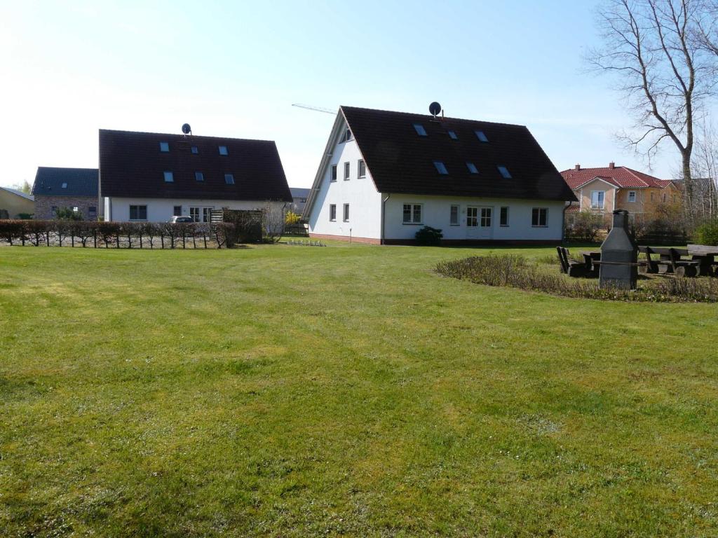 a white house with a black roof and a grass field at Ferienwohnung Ankerplatz_VOLB in Ostseebad Karlshagen