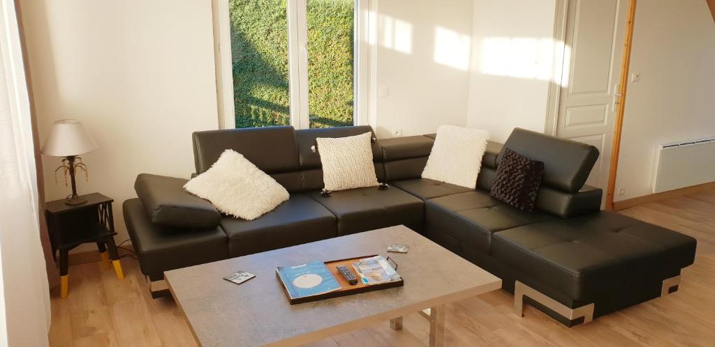 un salon avec un canapé noir et une table dans l'établissement Gîte du Port de Saint Valery, à Saint-Valery-sur-Somme