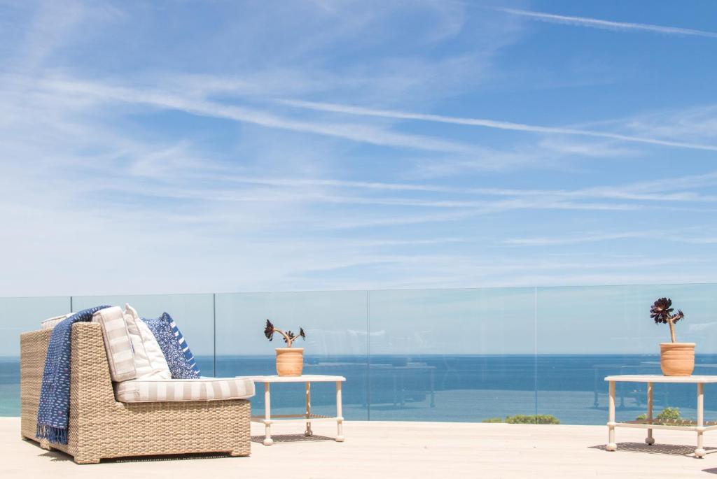 a rattan chair and tables in front of the ocean at Boskerris Hotel in St Ives