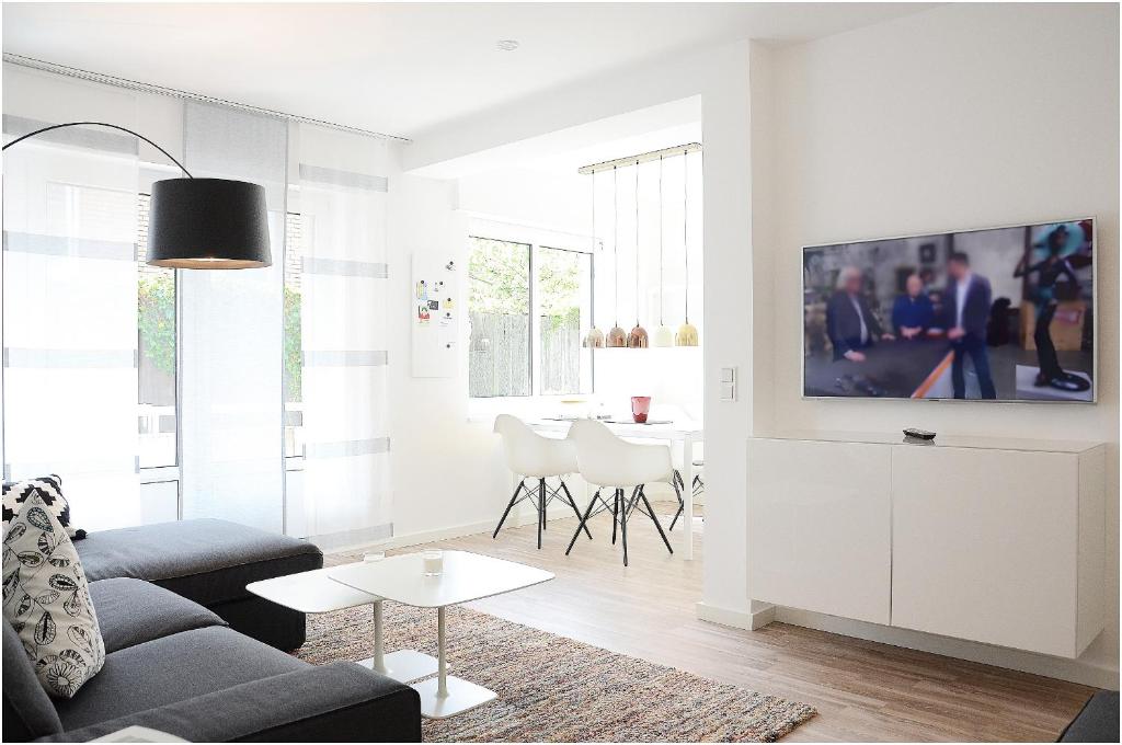 ein Wohnzimmer mit einem Sofa und einem TV an der Wand in der Unterkunft Suite Gartenstraße im hellen Ambiente in Norderney