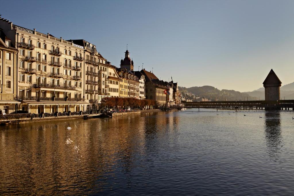 einen Fluss in einer Stadt mit Gebäuden und einer Brücke in der Unterkunft Hotel des Balances in Luzern