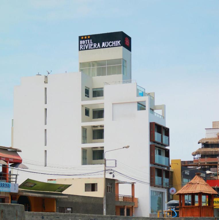 a tall white building with a sign on it at Hotel Riviera Muchik in Huanchaco