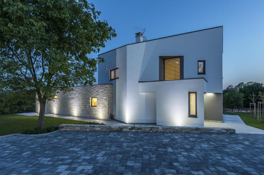 a white house with a brick driveway at Contemporary Villa Nada with Pool and Sauna in Tinjan