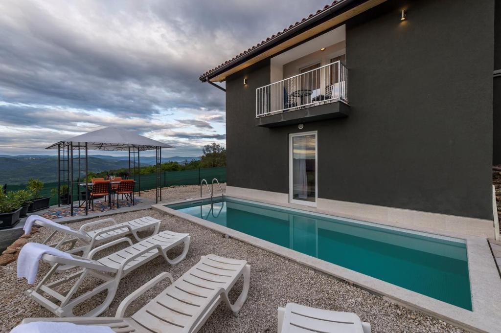 a house with a swimming pool with chairs and a table at Villa Art House with Pool in Vižinada