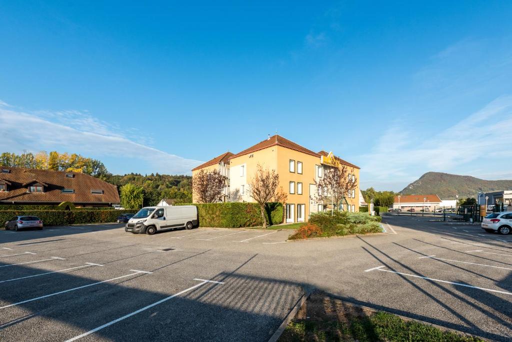 a parking lot with a car parked in front of a building at Premiere Classe Annecy Nord - Epagny in Épagny