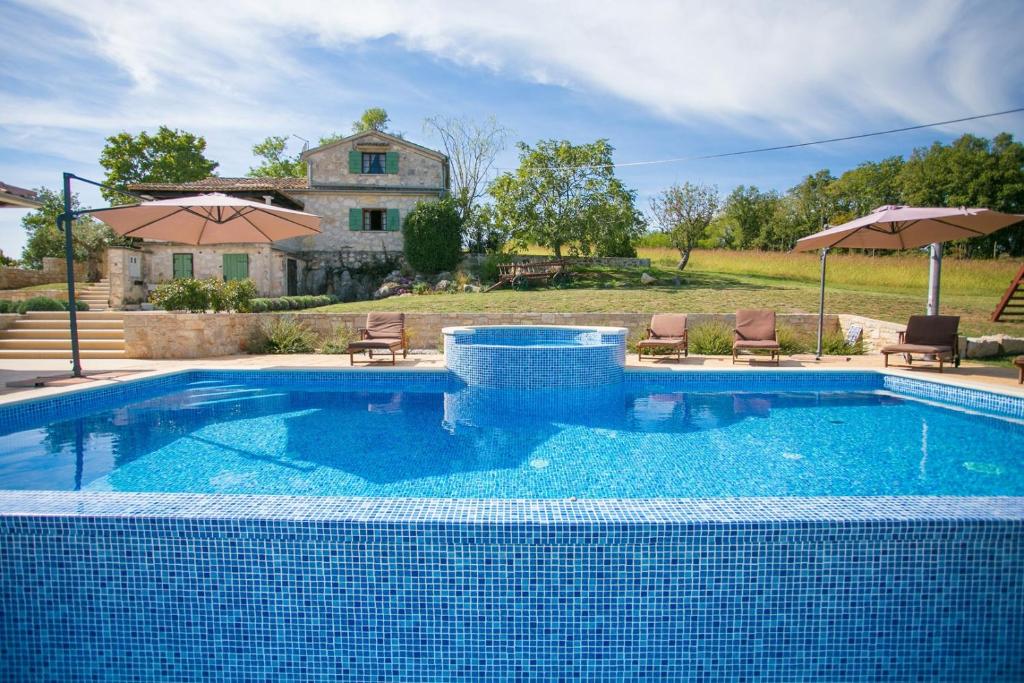a swimming pool in front of a house at Unique Villa Bošket with Pool and Jacuzzi surrounded by Nature in Vižinada