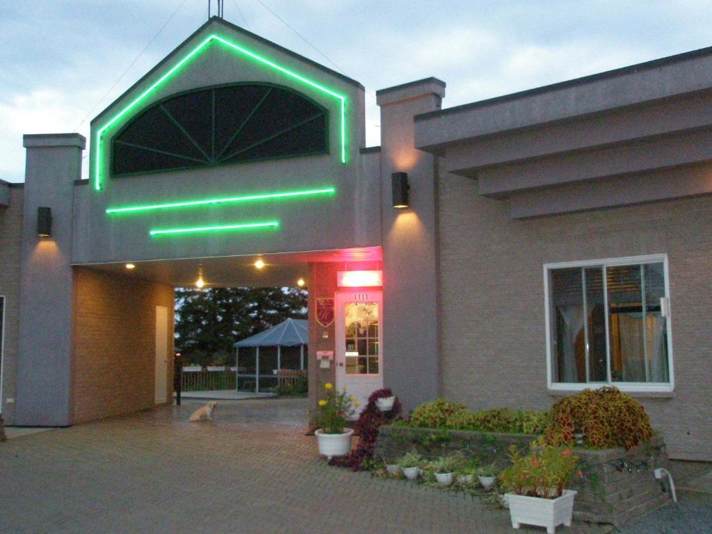 une femme assise à l'extérieur d'un bâtiment avec un panneau vert dans l'établissement Motel Normandie, à Louiseville