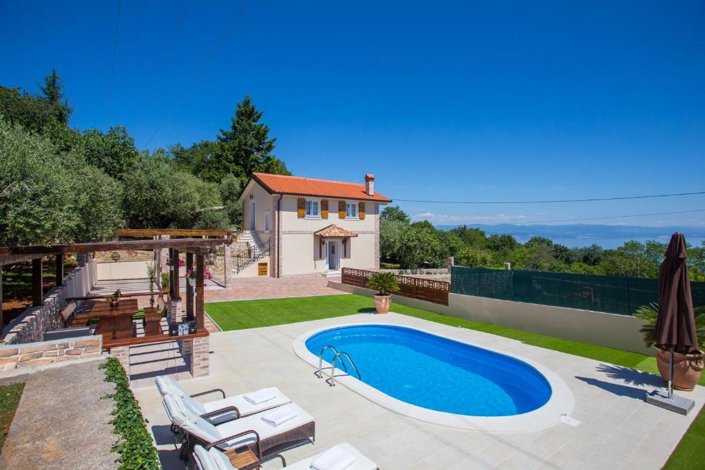 a backyard with a swimming pool and a house at Villa Olive with Pool and Sea View in Ičići