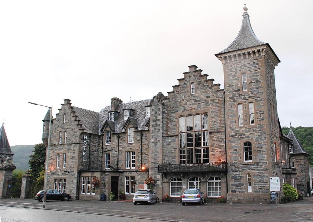 ein altes Steingebäude mit davor geparkt in der Unterkunft Birnam Hotel in Dunkeld