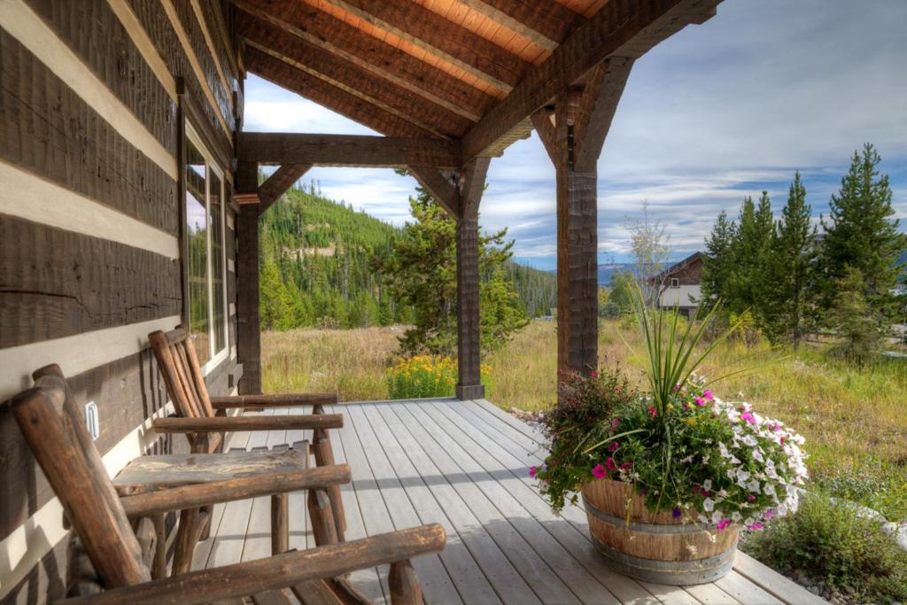 大天空市的住宿－Camp Arrowhead Cabin，一个带两把椅子和鲜花的房屋门廊