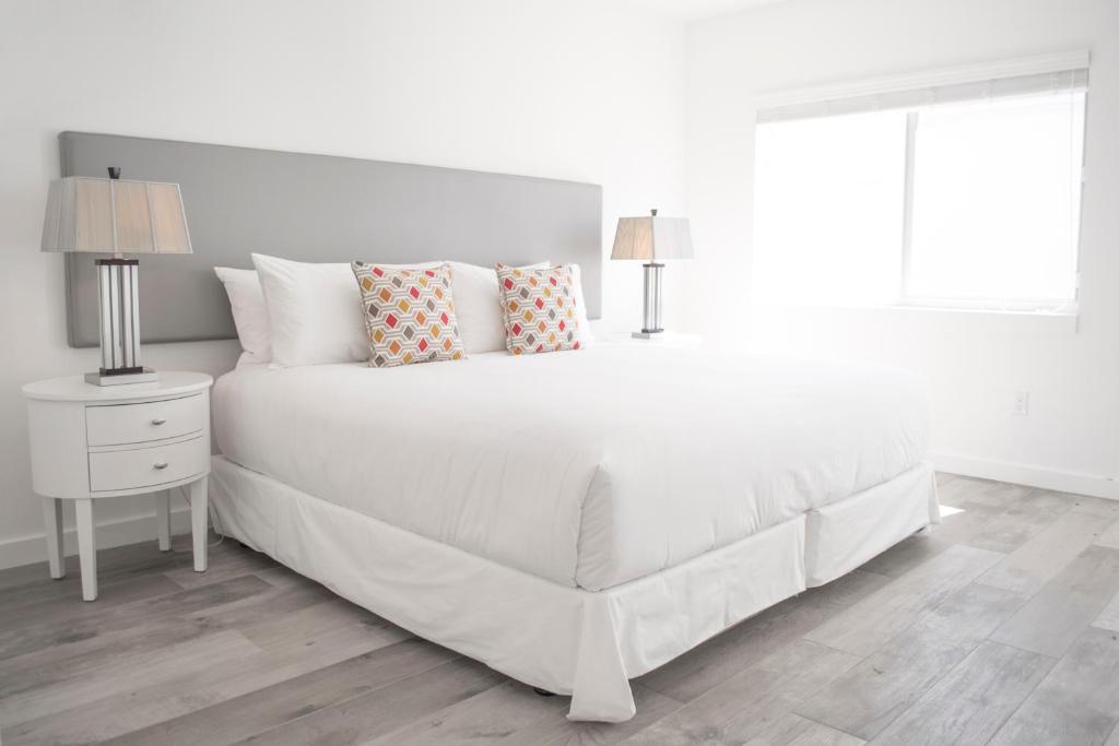 een witte slaapkamer met een wit bed met kussens bij Sobe Lux in Miami Beach