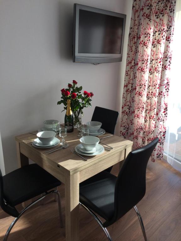 a dining room table with chairs and a television at Apartament Pod sanockim zamkiem in Sanok