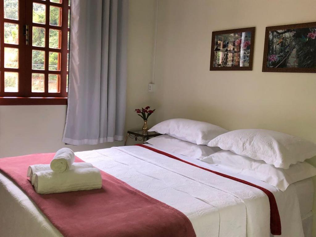 ein Schlafzimmer mit einem großen Bett mit zwei Handtüchern darauf in der Unterkunft Hospedaria Aconchego in Santa Teresa