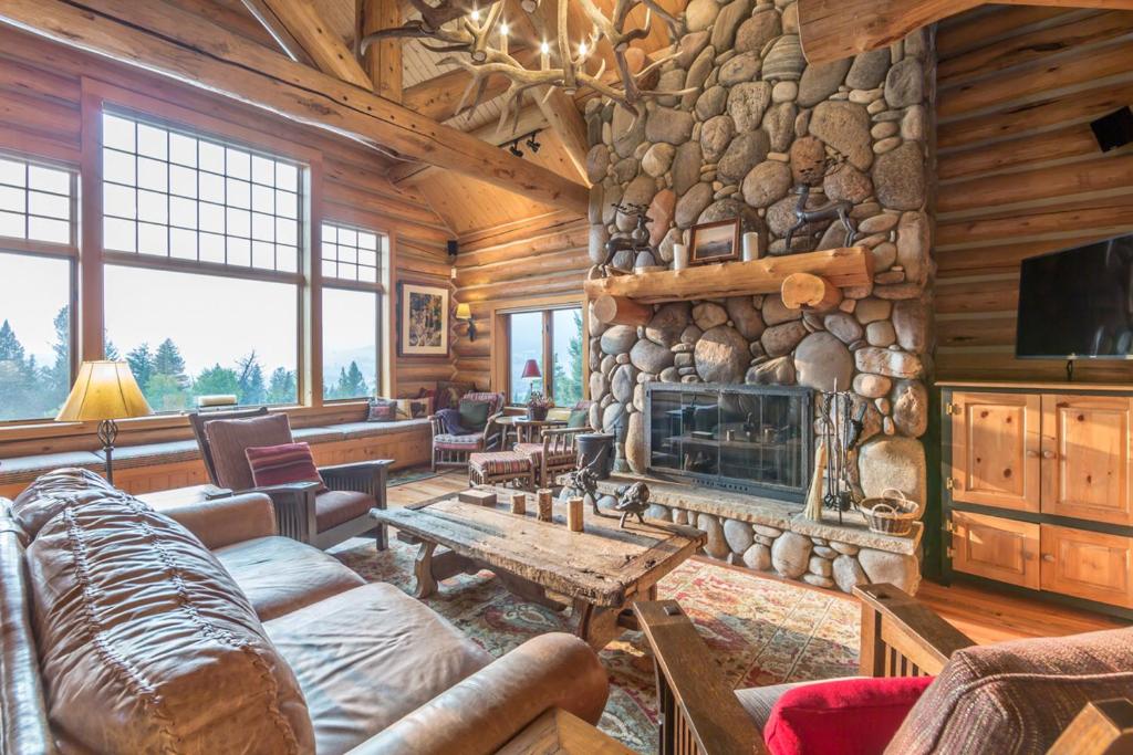 a living room with a stone fireplace in a log cabin at Huckleberry Hideaway in Big Sky