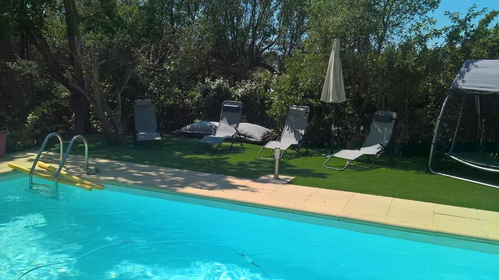 a swimming pool with chairs and an umbrella at DIVA in Roquebrune-sur-Argens