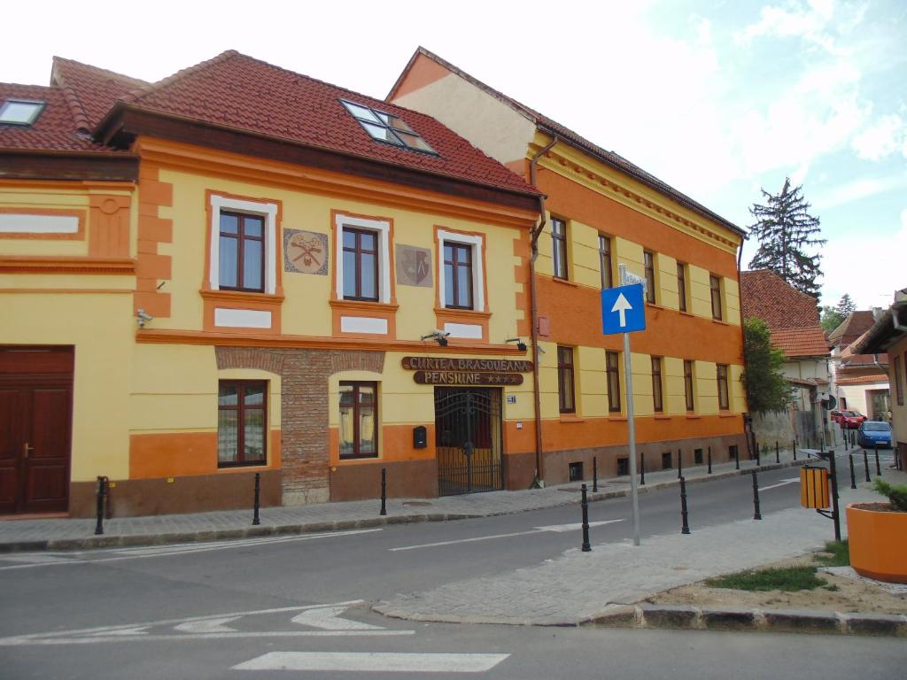 un edificio amarillo y naranja al lado de una calle en Curtea Brasoveana, en Brasov