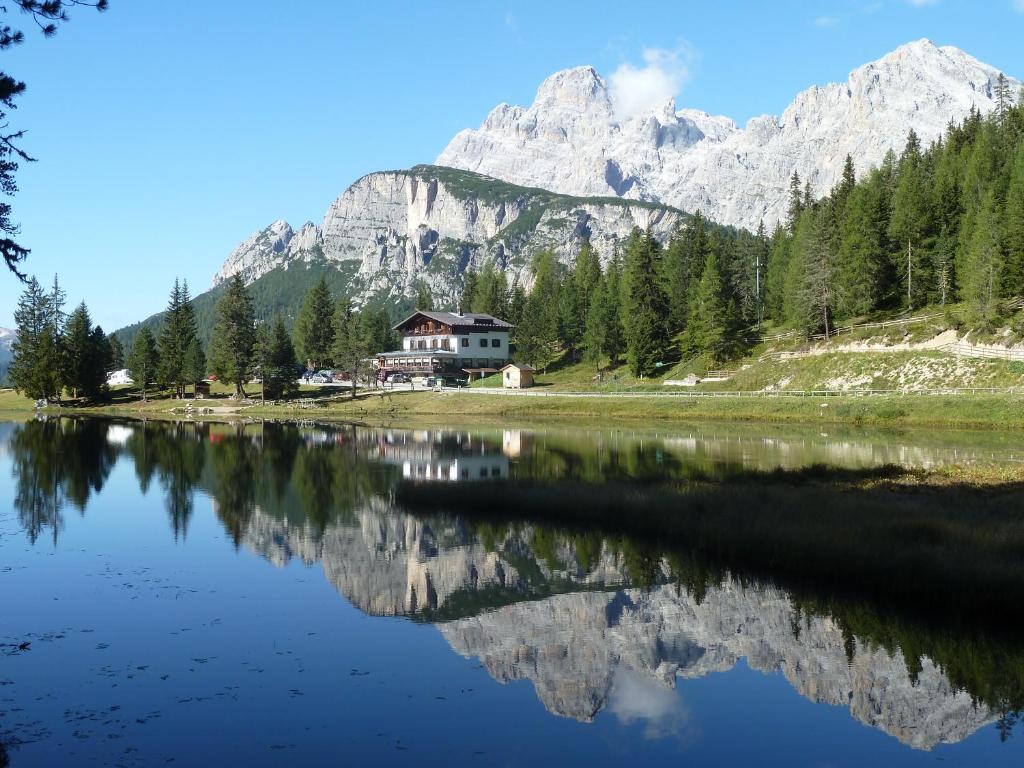 a reflection of a house in a lake with mountains at Albergo Chalet Lago Antorno in Misurina