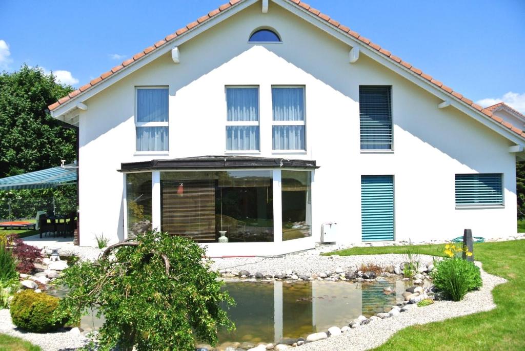 a white house with a pond in front of it at Bed and Breakfast La Petite Thielle in Cressier