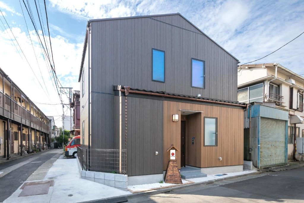a small house with a metal facade on a street at IKIDANE Cozy Hotel Haneda Airport in Tokyo