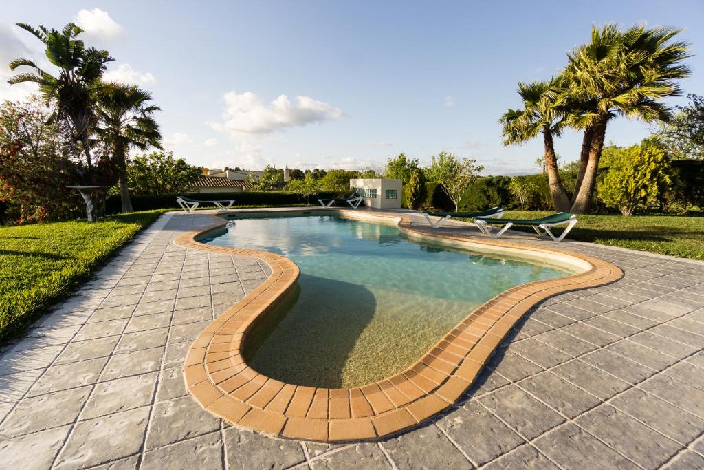 a swimming pool with a brick path around it at Horta Nova in Lagos