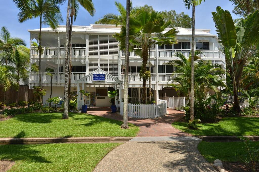 a large white building with palm trees in front of it at The White House Port Douglas in Port Douglas