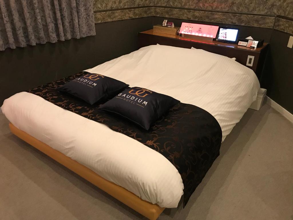 Una cama con almohadas blancas y negras. en Hotel Gaudium (Adult Only) en Kuki