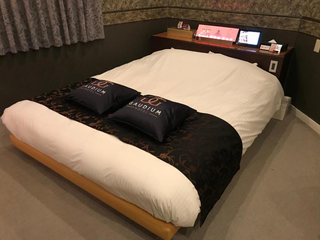 a bed with black and white pillows on it at Hotel Gaudium (Adult Only) in Kuki