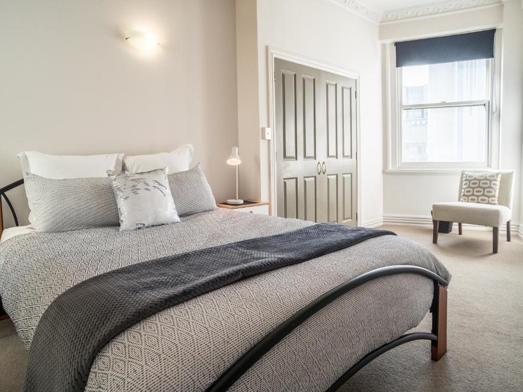 ein Schlafzimmer mit einem Bett, einem Stuhl und einem Fenster in der Unterkunft U Suites on Manners in Wellington