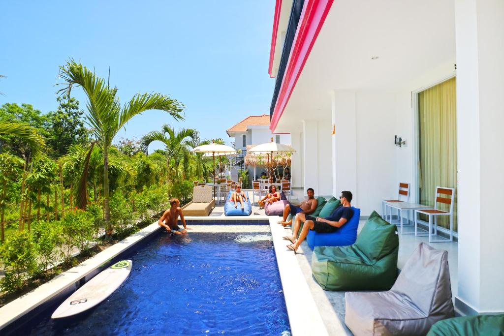grupa ludzi siedzących wokół basenu w obiekcie Margarita Surf Hostel w mieście Canggu