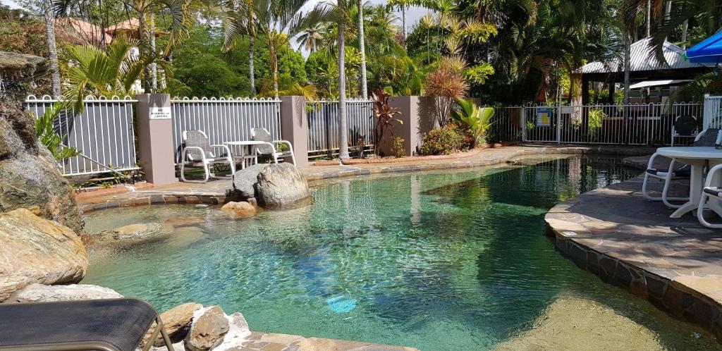 una piscina de agua con mesa y sillas. en Reef Palms, en Cairns